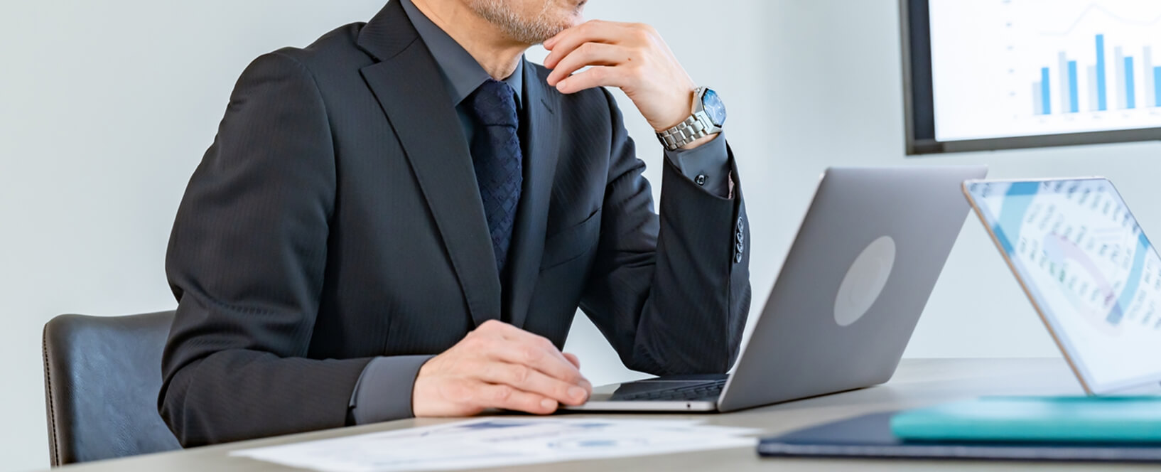 スーツ姿の男性がノートパソコンで資料を確認している様子